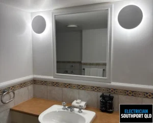 A clean bathroom with a modern round mirror above a sink and neatly arranged accessories